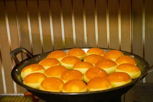 Mini bread dough donuts are fried in oil on a griddle photo