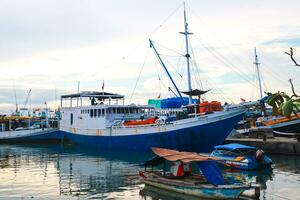 Several wooden boats and cargo ships moored at the traditional port while waiting for loading and unloading photo