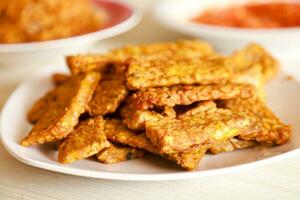 Tempe goreng or fried tempeh is served on a plate along with sambal photo