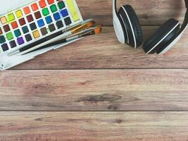 flat lay of headphones and artist workspace. Drawing tools, stationary supplies on wooden table background with copy space. hobby or leisure concept. photo