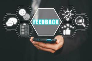 Feedback concept, Business person hand holding smartphone with feedback icon on virtual screen. photo