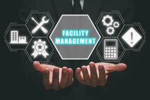 Facility management concept, Business person hand holding facility management icon on virtual screen. photo