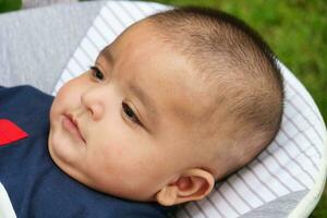 Close Up Shot of Cute Asian Pakistani 4 Months Old Baby Boy, Who is Enjoying at Home Garden at Luton City of England UK. Image Was Captured on July 23rd, 2023 photo