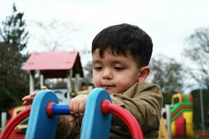 linda asiático pakistaní bebé es disfrutando el hermosa soleado día a Wardown niños y público parque de lutón pueblo de Inglaterra Reino Unido. bajo ángulo imagen estaba capturado en abril 03, 2023 foto