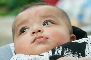 Close Up Shot of Cute Asian Pakistani 4 Months Old Baby Boy, Who is Enjoying at Home Garden at Luton City of England UK. Image Was Captured on July 23rd, 2023 photo