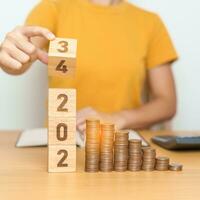 flipping 2023 to 2024 year block with Coins stack. Money, Budget, tax, investment, financial, savings and New Year Resolution concepts photo