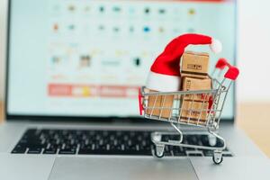 Christmas Online Shopping concept. Boxes with shopping cart on a laptop computer. Sale and discount during Christmas and New Year holiday, ecommerce, shipping delivery, logistics and Cyber Monday photo