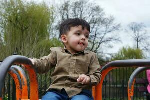 Cute Asian Pakistani Baby is Enjoying The Beautiful Sunny Day at Wardown Children and Public Park of Luton Town of England UK. Low Angle  Image Was Captured on April 03rd, 2023 photo