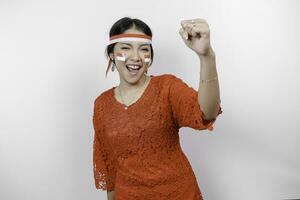 A young Asian woman with a happy successful expression wearing red kebaya and headband isolated by white background. Indonesia's independence day concept. photo