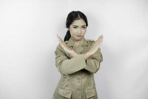 Young Asian woman wearing a brown uniform shows crossed hands or stop gesture, isolated white background photo