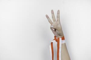 hands gesturing signs of number wearing Indonesian red and white ribbon. Indonesia's independence day concept photo