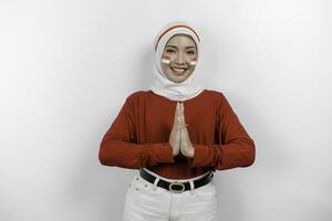 un simpático indonesio musulmán mujer es vistiendo rojo parte superior y blanco hijab gesticulando tradicional saludo a celebrar Indonesia independencia día. aislado por blanco antecedentes. foto