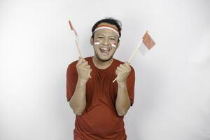 Happy smiling Indonesian man holding Indonesia's flag to celebrate Indonesia Independence Day isolated over white background. photo