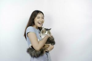 Portrait of young Asian woman holding cute angora cat with yellow eyes. Female hugging her cute long hair kitty isolated by white background. Adorable domestic pet concept. photo