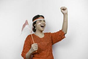 A young Asian woman with a happy successful expression wearing red kebaya and headband isolated by white background. Indonesia's independence day concept. photo