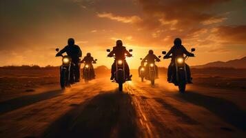 Motorcyclists riding on the road in the desert during sunset. photo