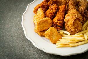 pollo frito con papas fritas y nuggets en un plato foto