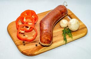 Tasty sausages and vegetables isolated over solid background photo