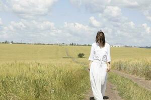 a woman in a white dress standing in a field photo