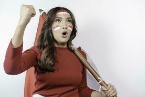 A young Asian woman with a happy successful expression wearing red top and headband while holding Indonesia's flag, isolated by white background. Indonesia's independence day concept. photo