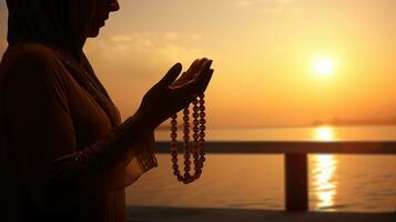 Muslim woman using beads to pray at sunrise outside. silhouette concept photo