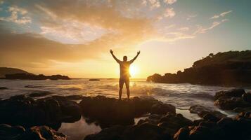 Happy man enjoying life on beach rocks by the ocean with arms wide open. silhouette concept photo