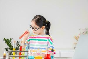 Asian little girl working with test tube science experiment in white classroom photo