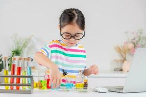 Asian little girl working with test tube science experiment in white classroom photo