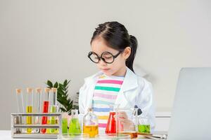 Asian little girl working with test tube science experiment in white classroom photo