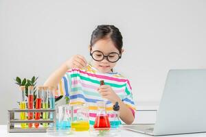 asiático pequeño niña trabajando con prueba tubo Ciencias experimentar en blanco salón de clases foto