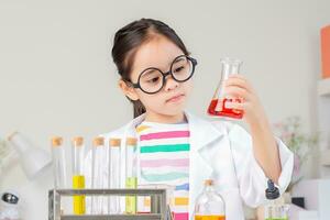 Asian little girl working with test tube science experiment in white classroom photo