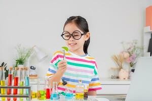 asiático pequeño niña trabajando con prueba tubo Ciencias experimentar en blanco salón de clases foto