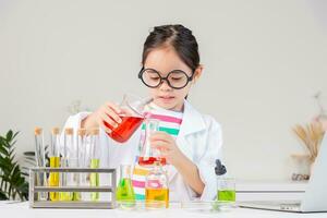 Asian little girl working with test tube science experiment in white classroom photo