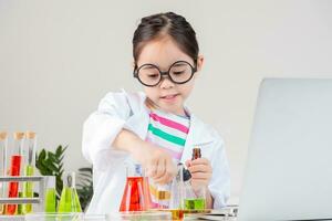 Asian little girl working with test tube science experiment in white classroom photo