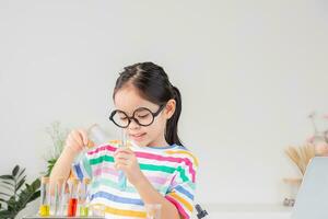 Asian little girl working with test tube science experiment in white classroom photo