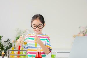 Asian little girl working with test tube science experiment in white classroom photo