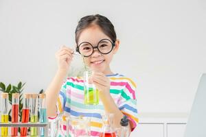 Asian little girl working with test tube science experiment in white classroom photo