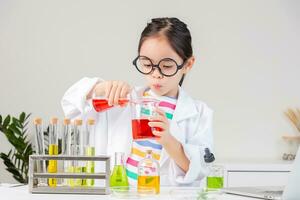 Asian little girl working with test tube science experiment in white classroom photo