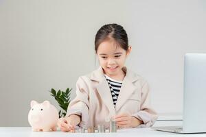 asiático pequeño linda niña vistiendo un crema traje analizando monedas Finanzas y inversión foto