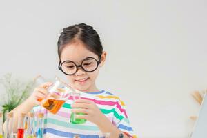 Asian little girl working with test tube science experiment in white classroom photo