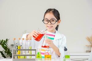 Asian little girl working with test tube science experiment in white classroom photo