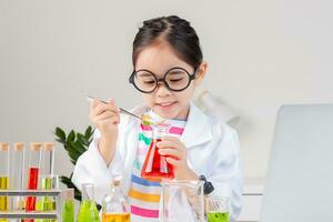 asiático pequeño niña trabajando con prueba tubo Ciencias experimentar en blanco salón de clases foto