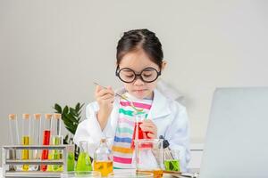 Asian little girl working with test tube science experiment in white classroom photo