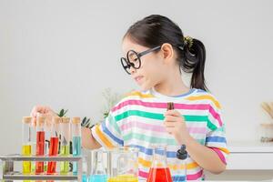 Asian little girl working with test tube science experiment in white classroom photo