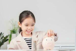 Asian little cute girl wearing a cream suit analyzing coins finance and investment photo