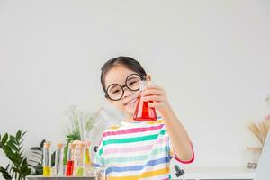 Asian little girl working with test tube science experiment in white classroom photo