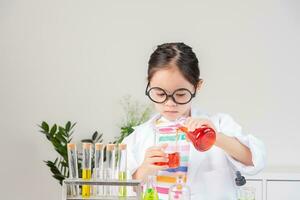 Asian little girl working with test tube science experiment in white classroom photo