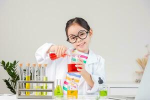 asiático pequeño niña trabajando con prueba tubo Ciencias experimentar en blanco salón de clases foto