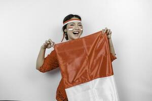 contento sonriente indonesio mujer vistiendo rojo kebaya y venda participación de indonesia bandera a celebrar Indonesia independencia día aislado terminado blanco antecedentes. foto