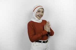 un simpático indonesio musulmán mujer es vistiendo rojo parte superior y blanco hijab gesticulando tradicional saludo a celebrar Indonesia independencia día. aislado por blanco antecedentes. foto